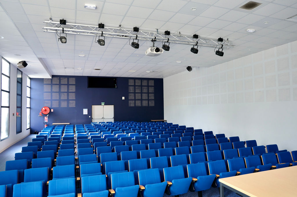 Vue de la scène vers les rangées de sièges bleus de l’auditorium
